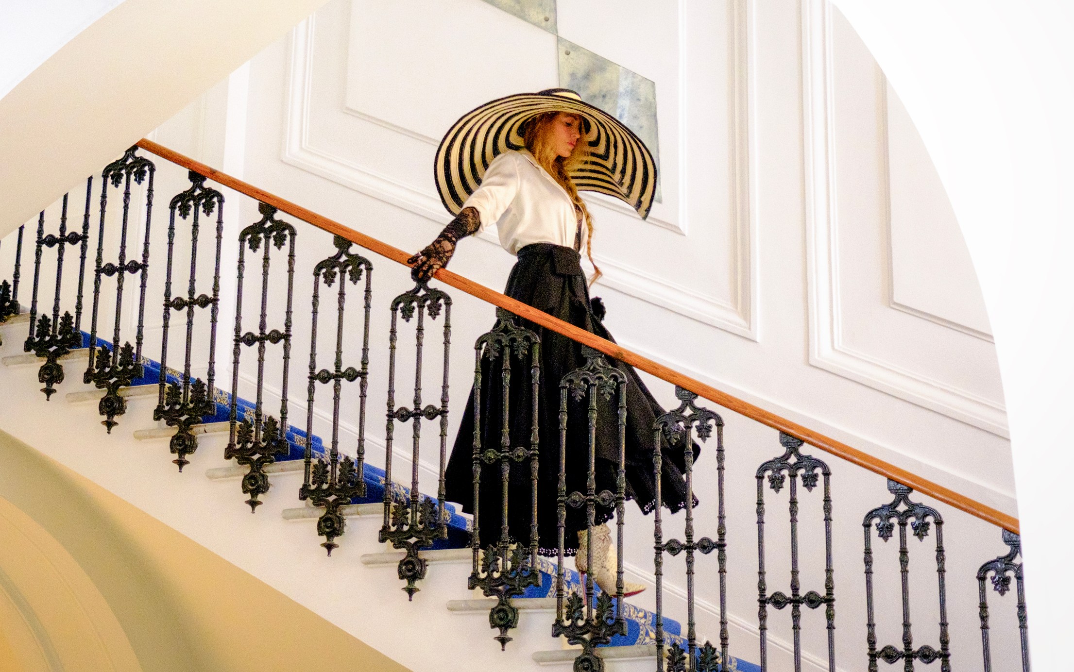 Blake Lively as Emily in Another Simple Favor ascending a grand staircase.