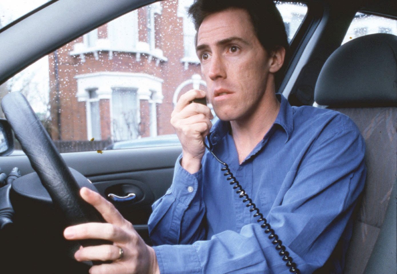 a man in a blue shirt is talking on a cell phone