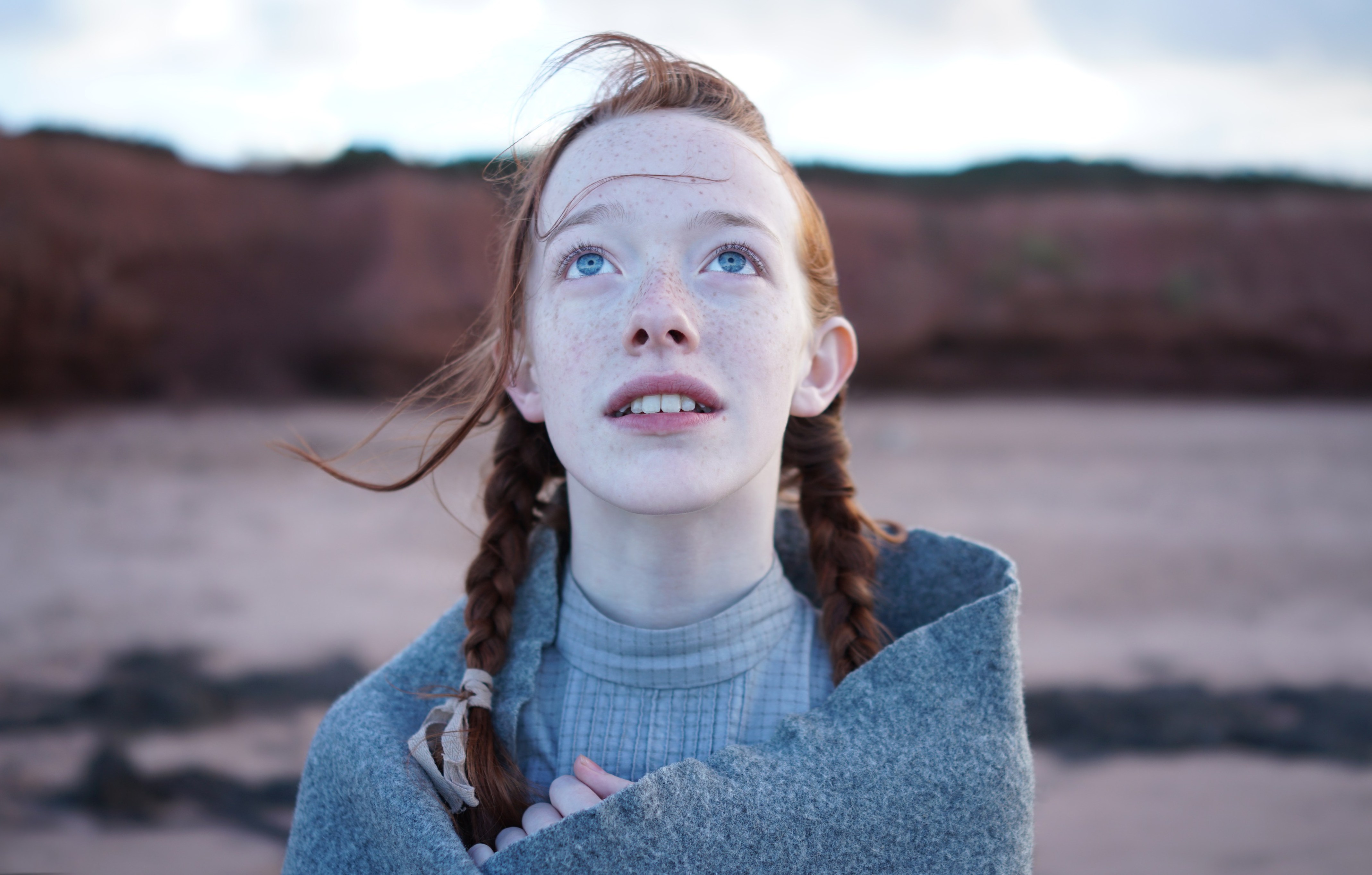 a girl with red hair and freckles looks up at the sky