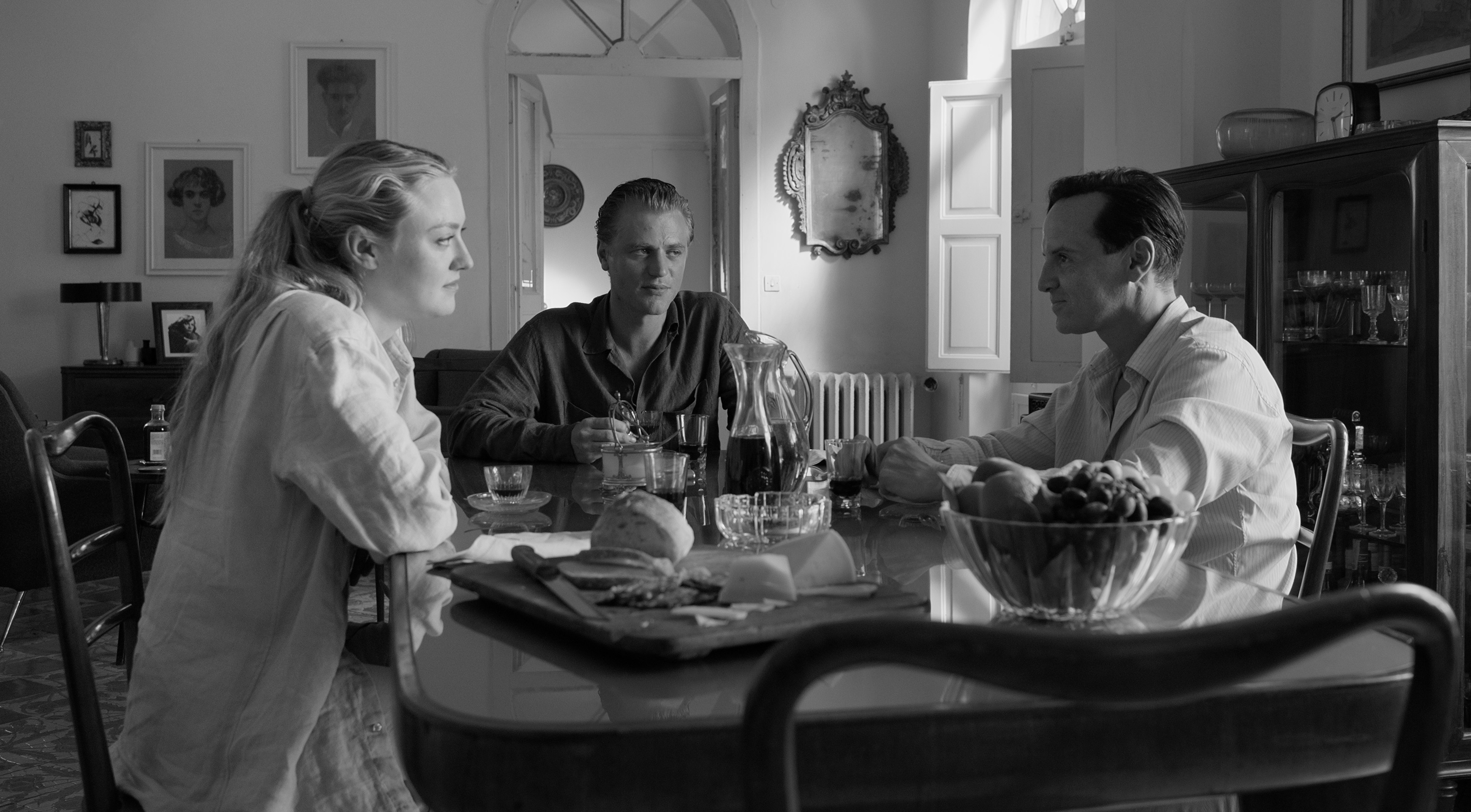 a black and white photo of three people sitting at a table