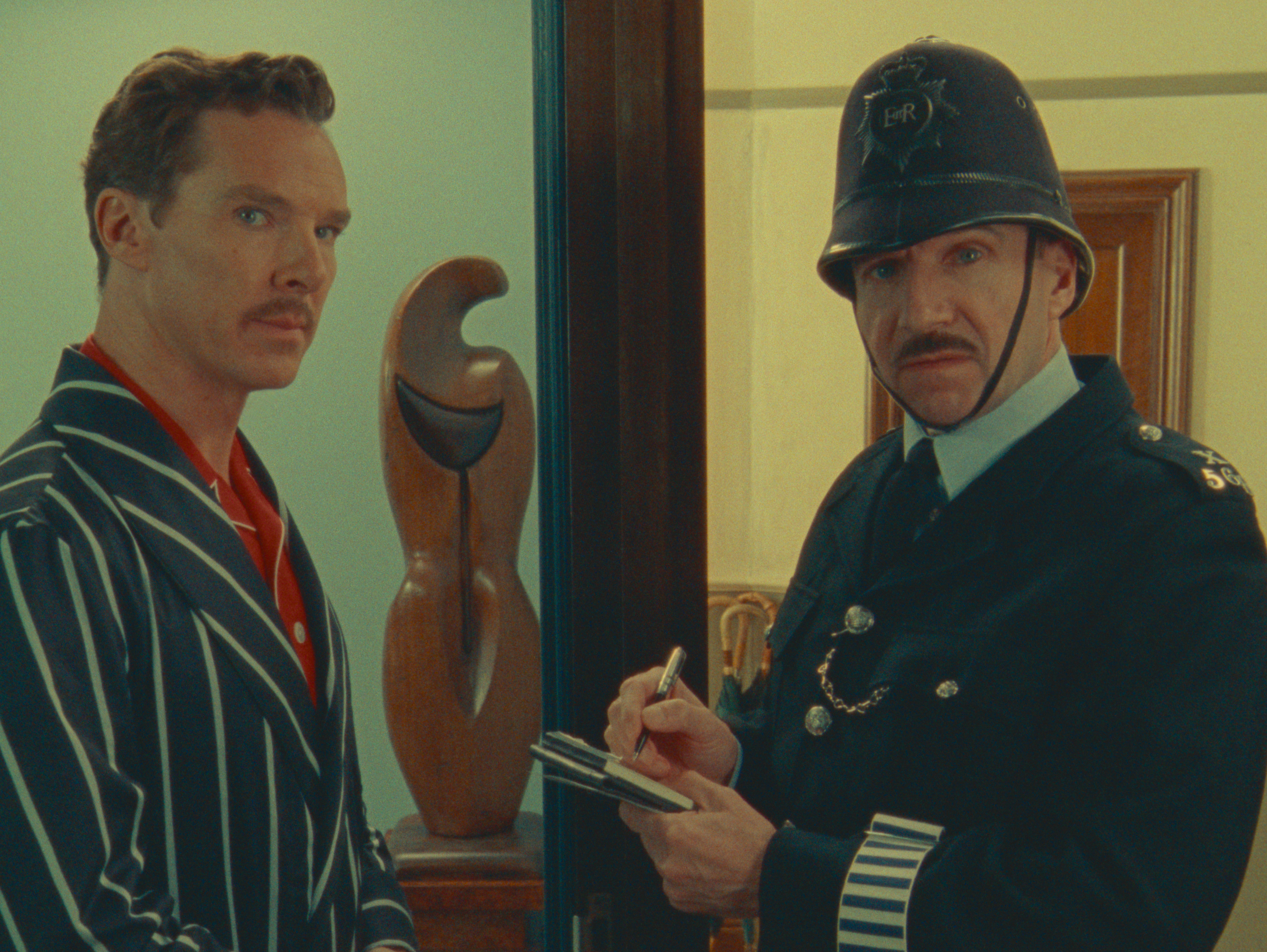 a man in a striped suit stands next to a police officer