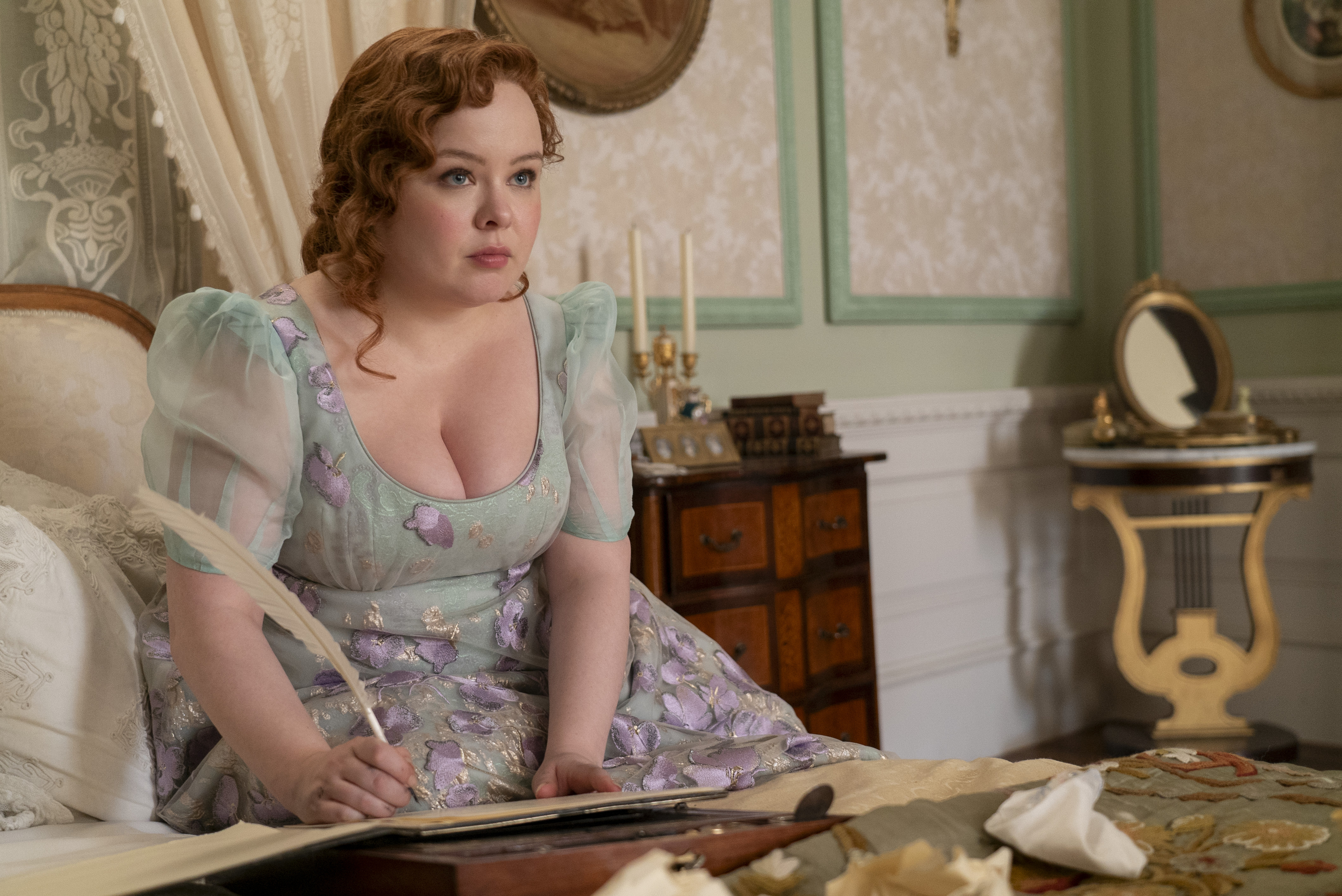 a woman sitting on a bed with a feather in her hand