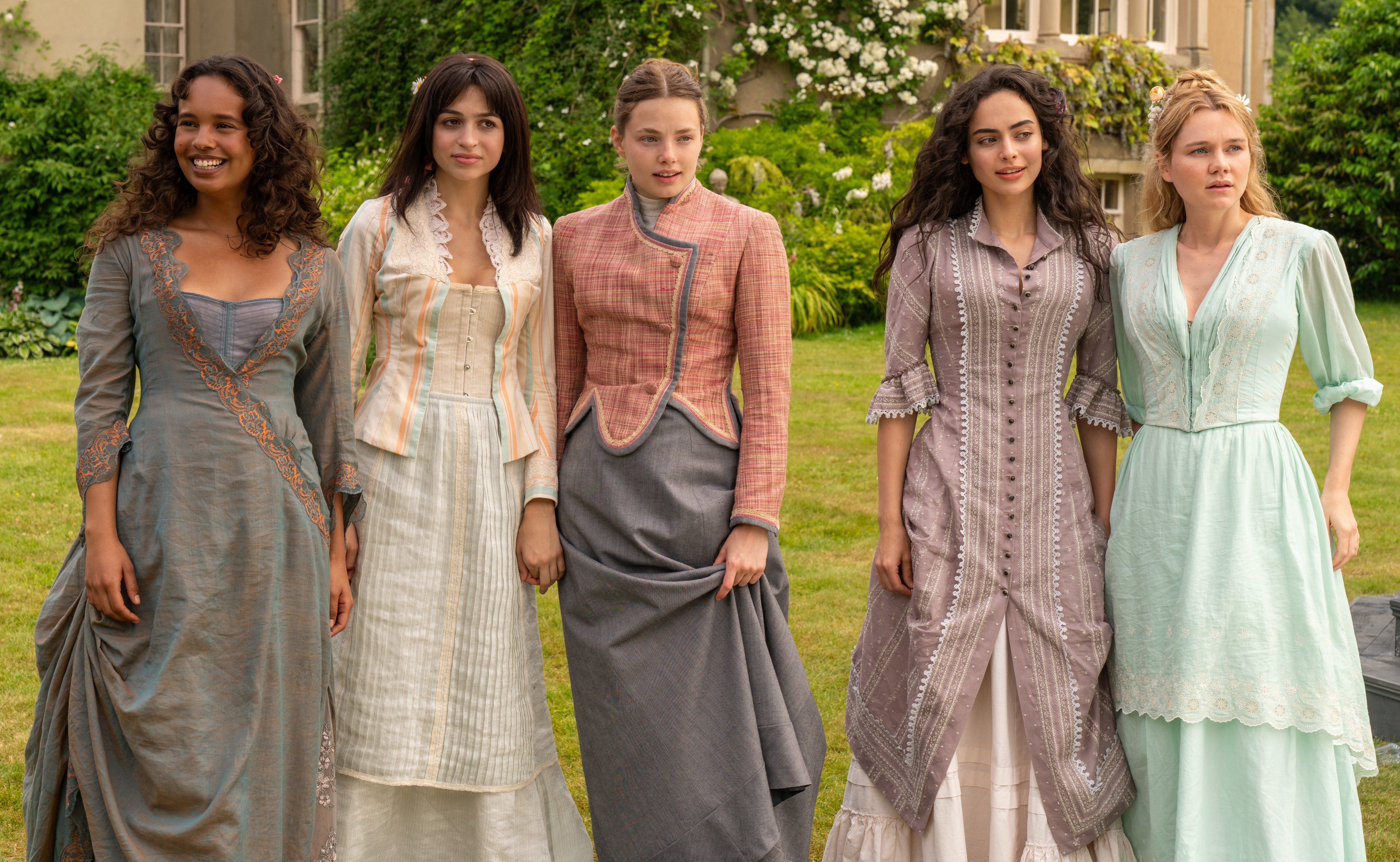 a group of women standing next to each other in front of a house