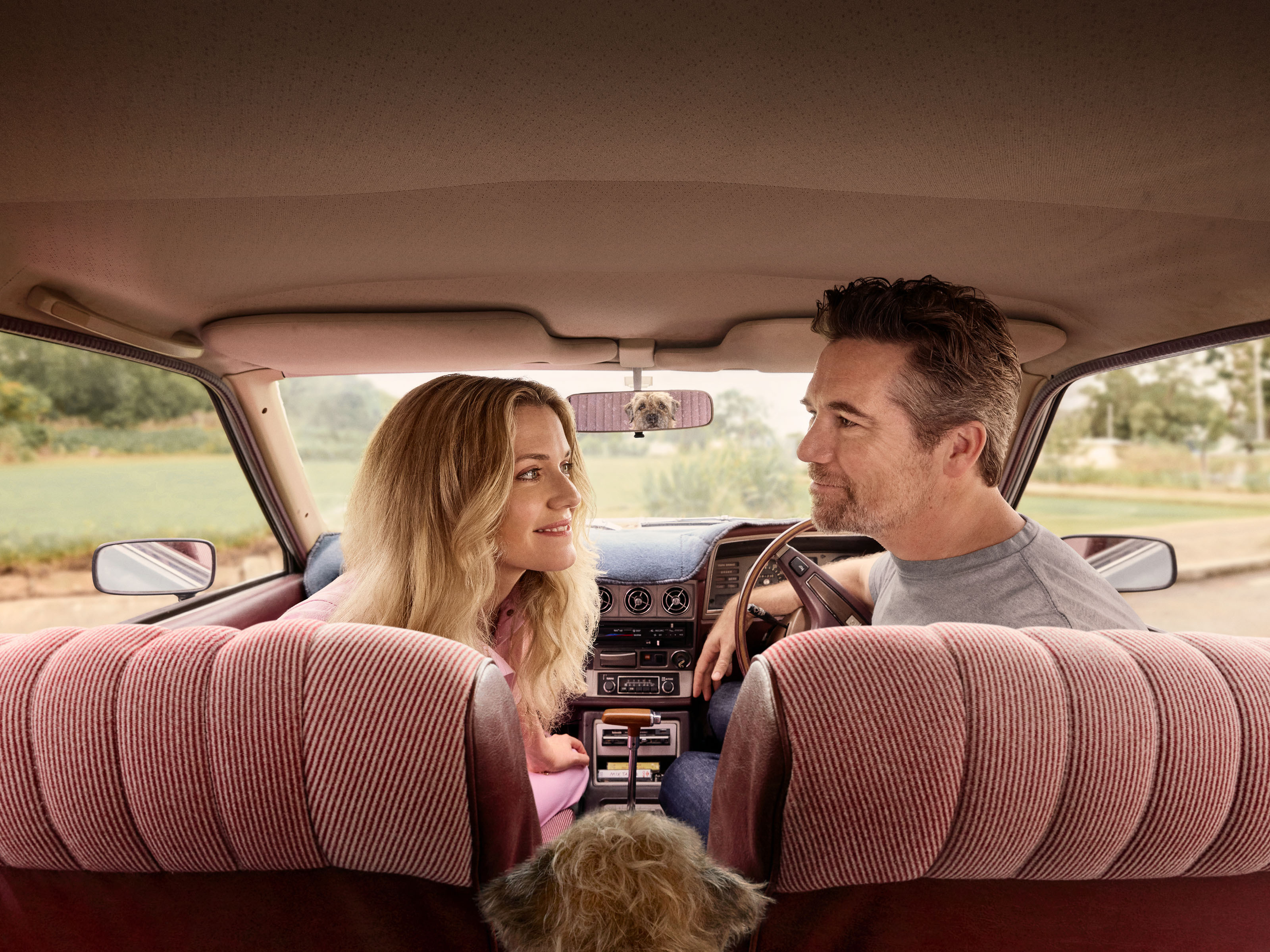 a man and a woman sit in the back seat of a car