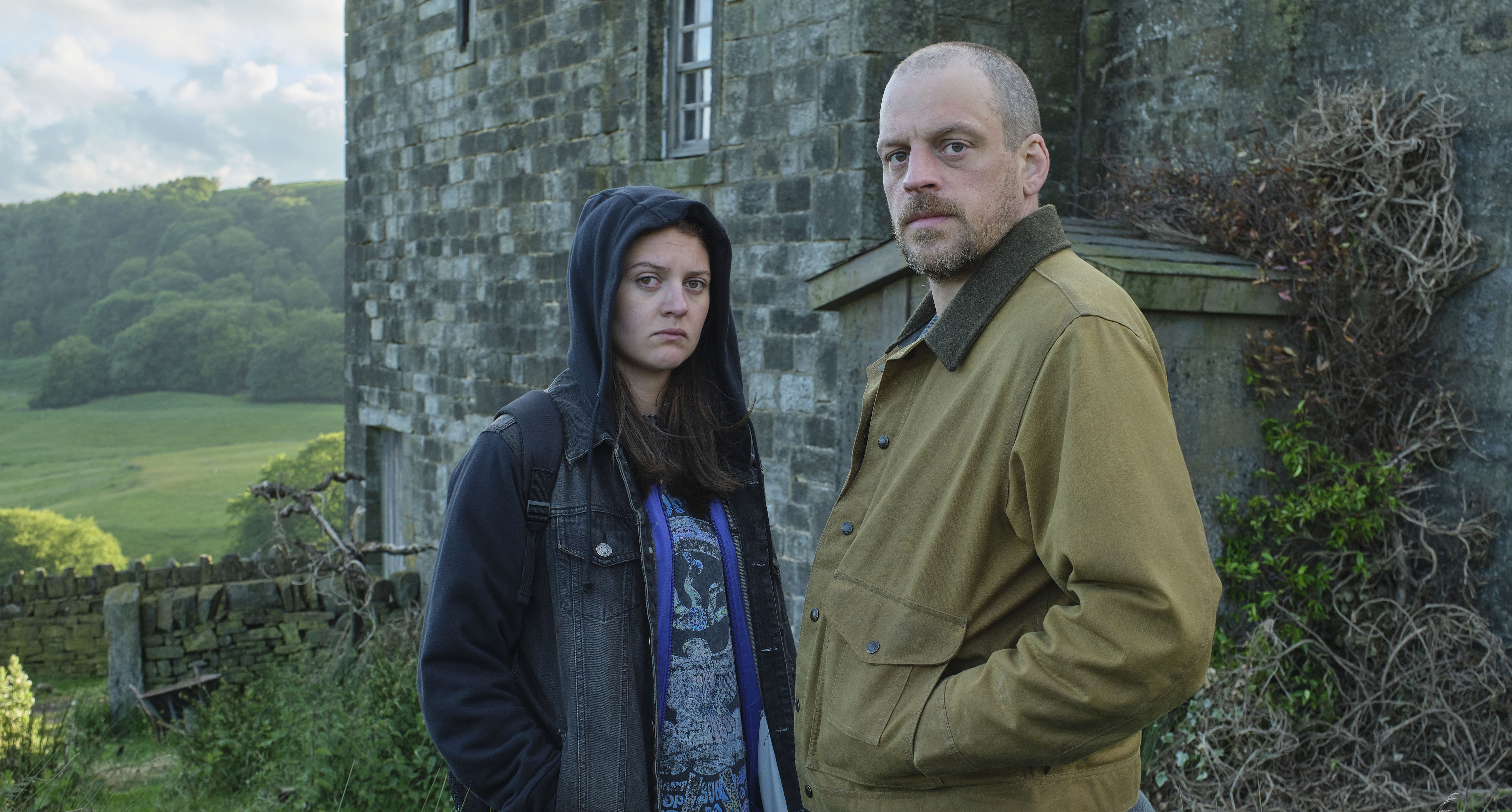 Carly and Daniel Brennan stand outside a stone building.