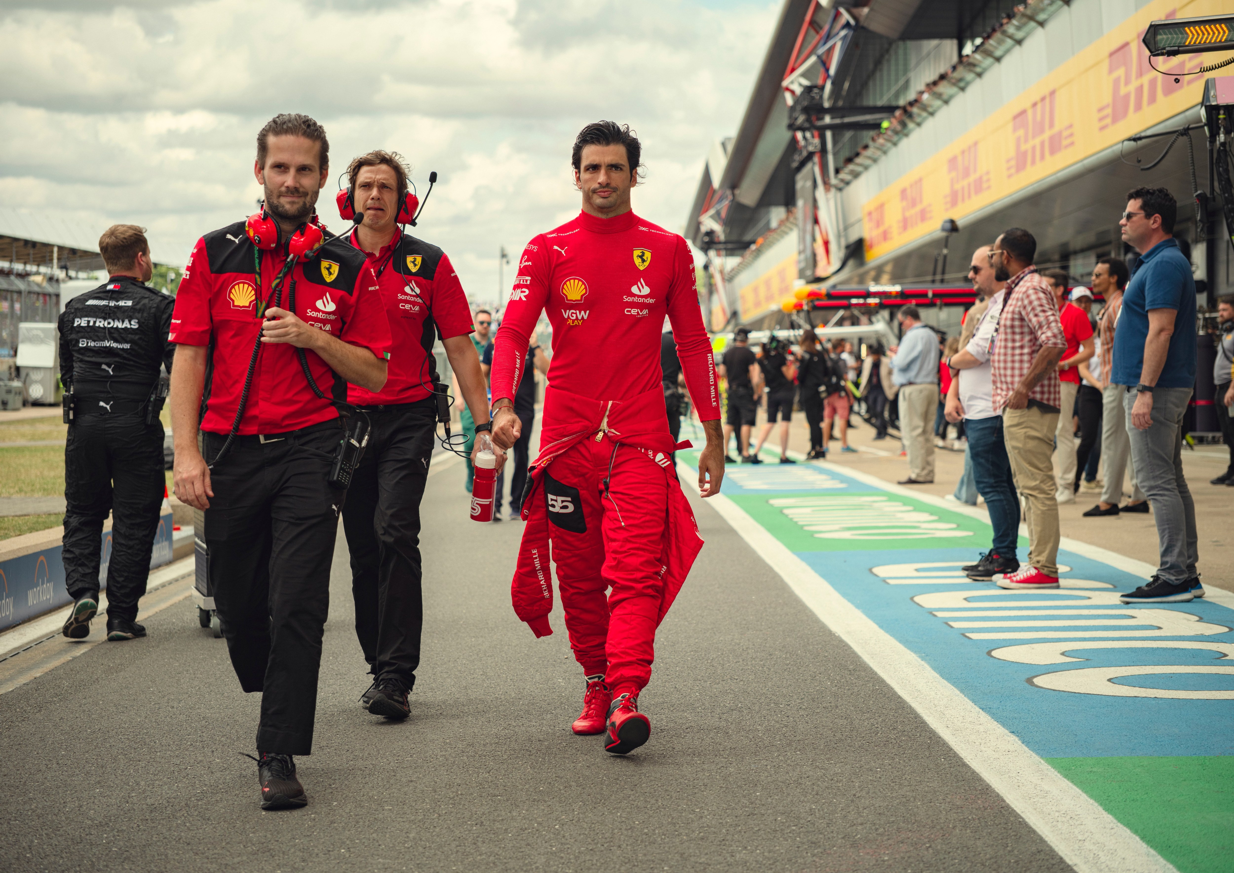 a man in a red ferrari uniform walks down a race track