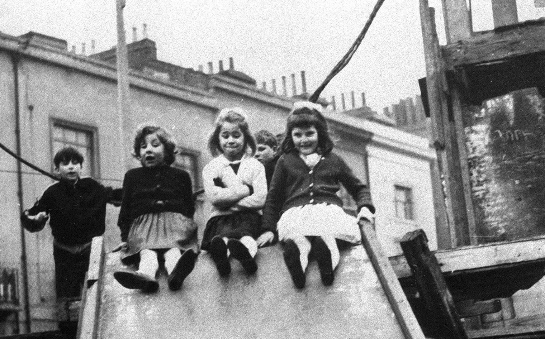 a black and white photo of children playing on a slide