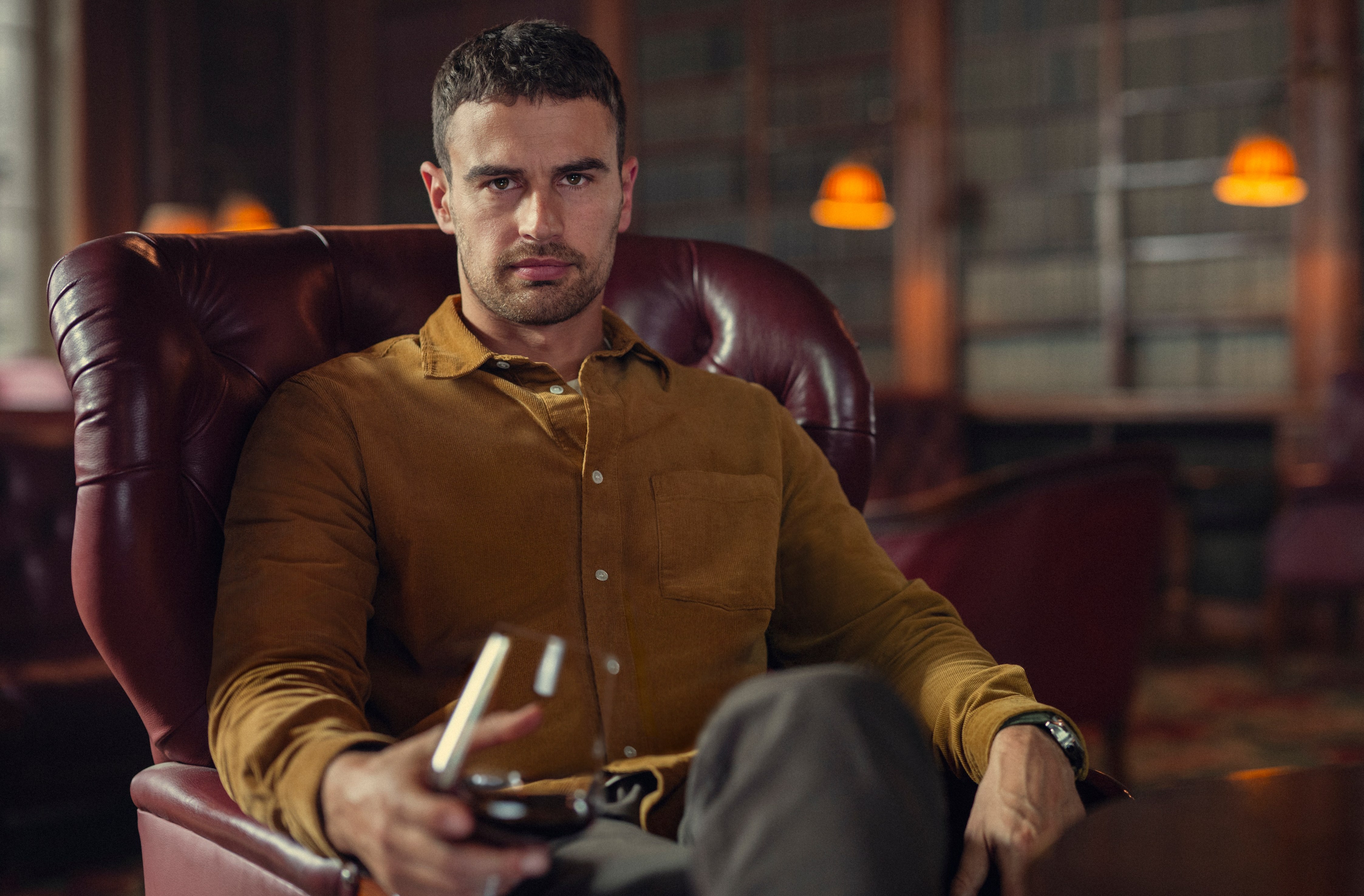 a man in a brown shirt is sitting in a chair