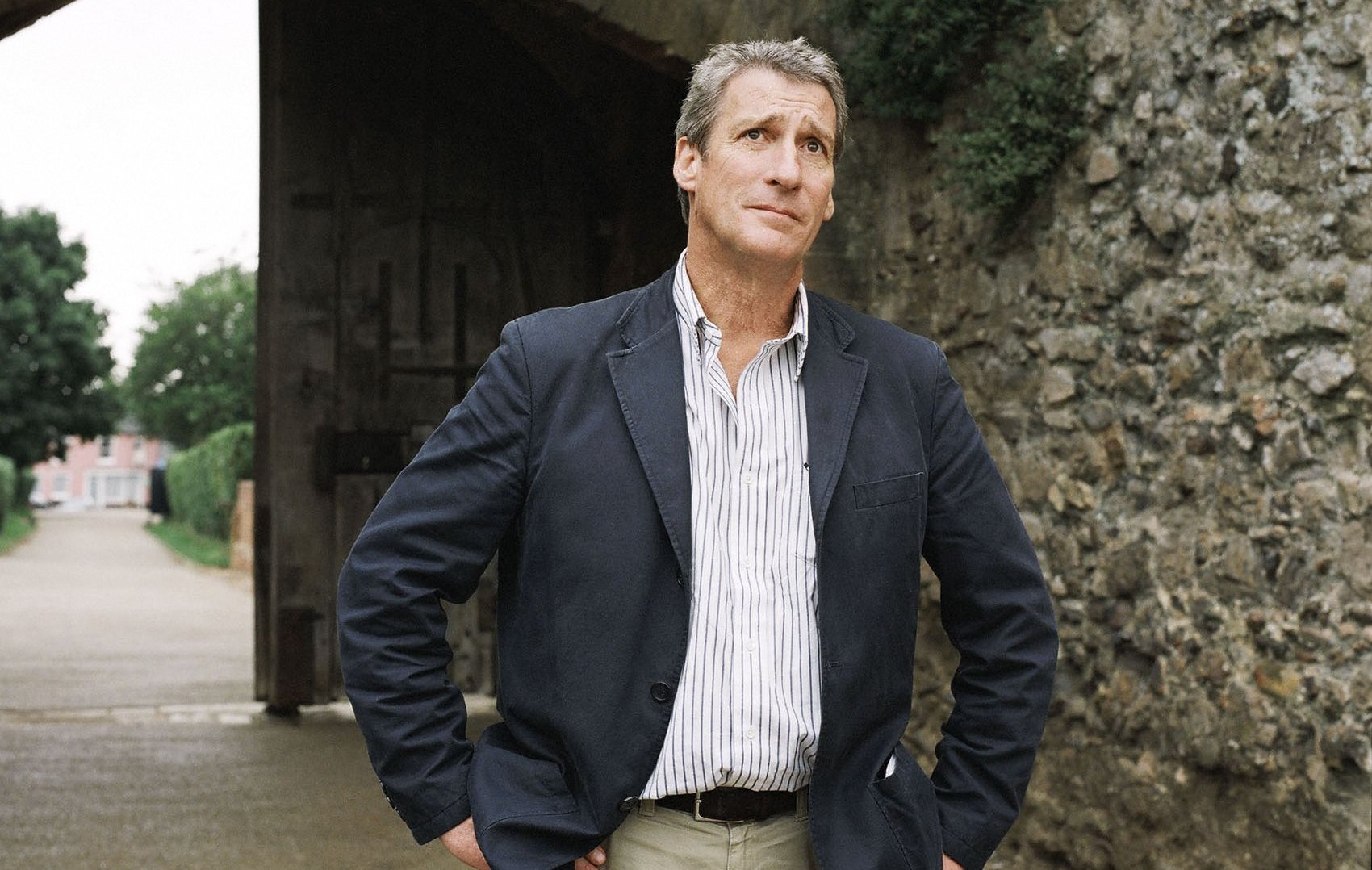 Jeremy Paxman standing outdoors near a stone archway.