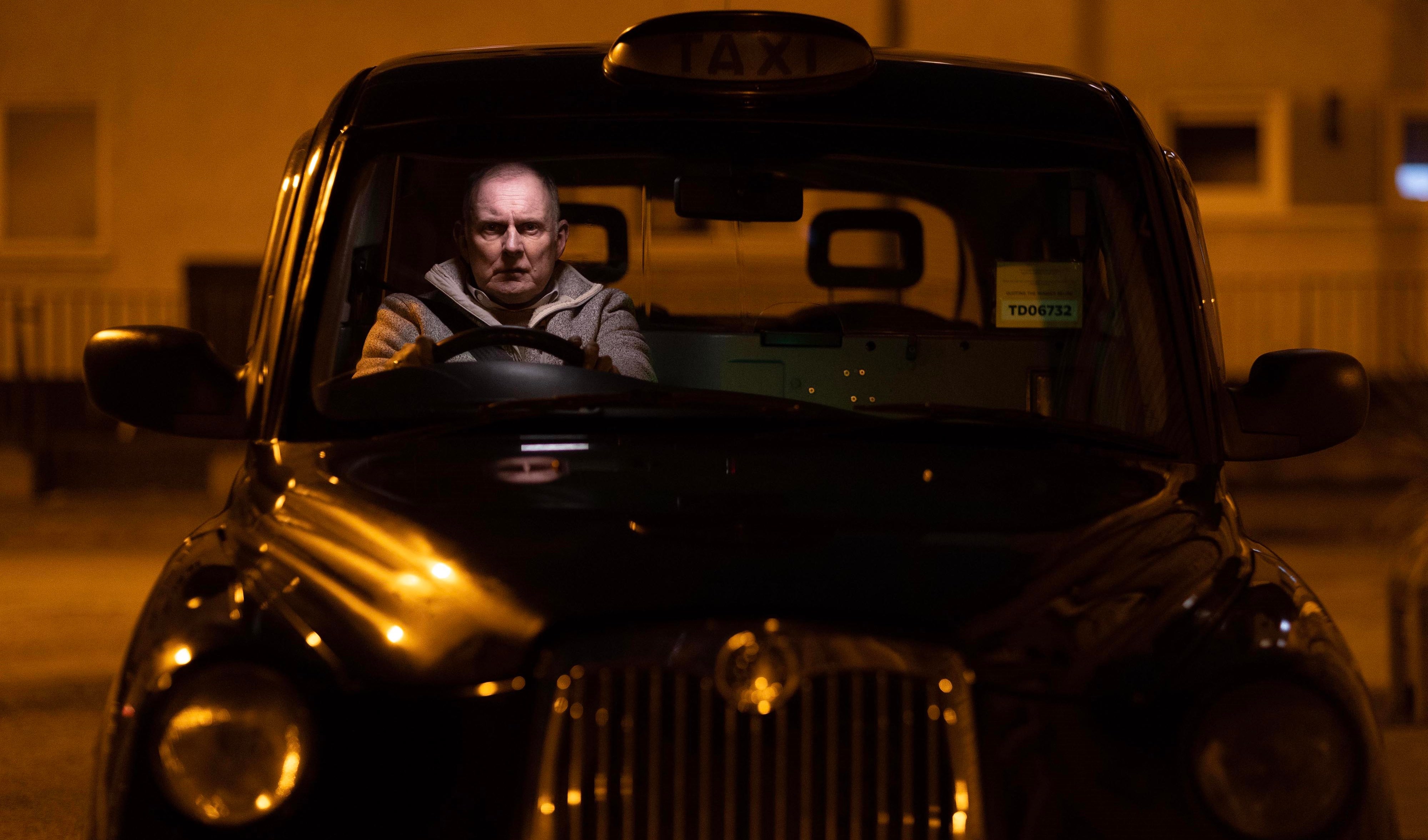 a man is driving a black taxi with a yellow sign that says tooe72