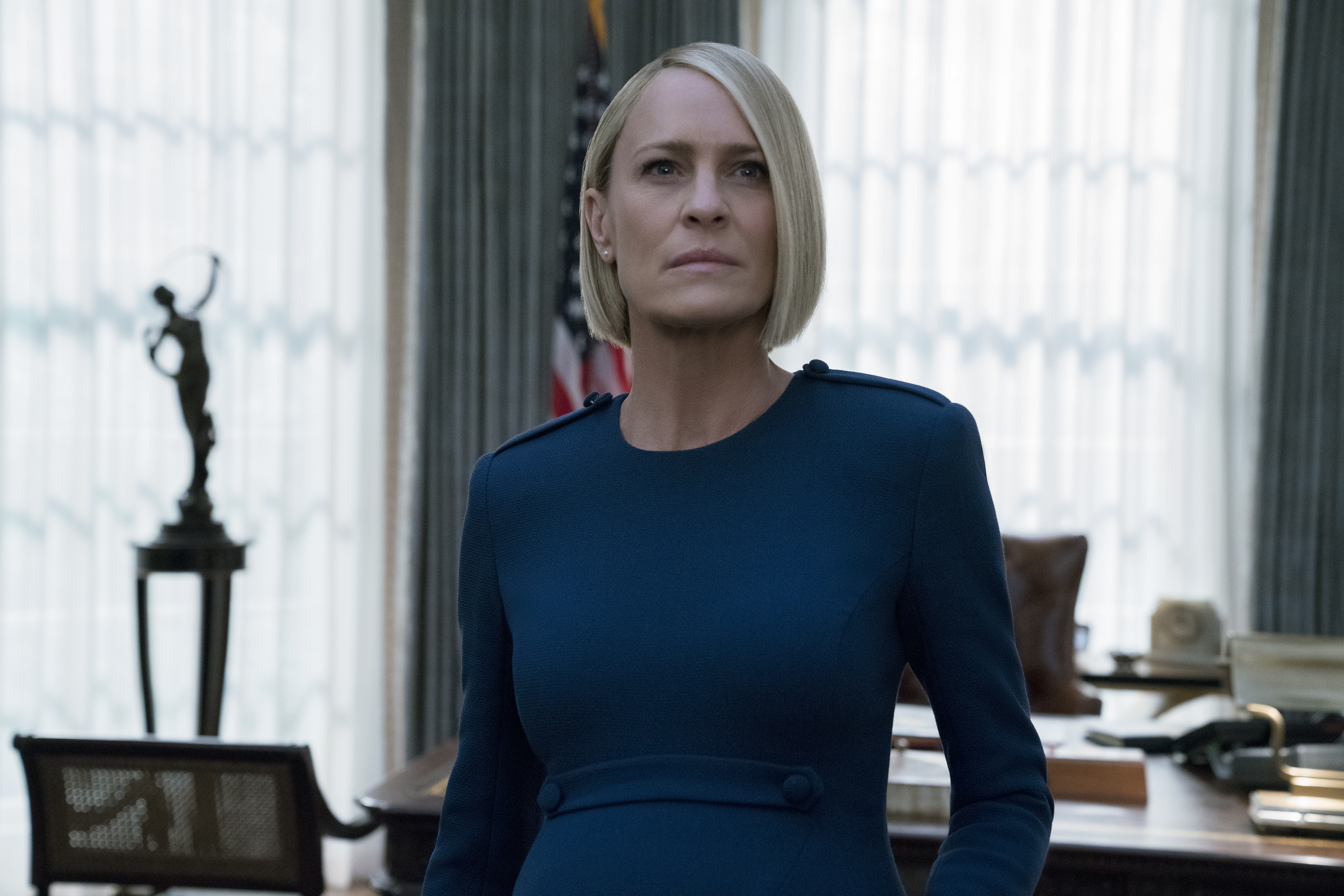 a woman in a blue dress stands in front of an american flag