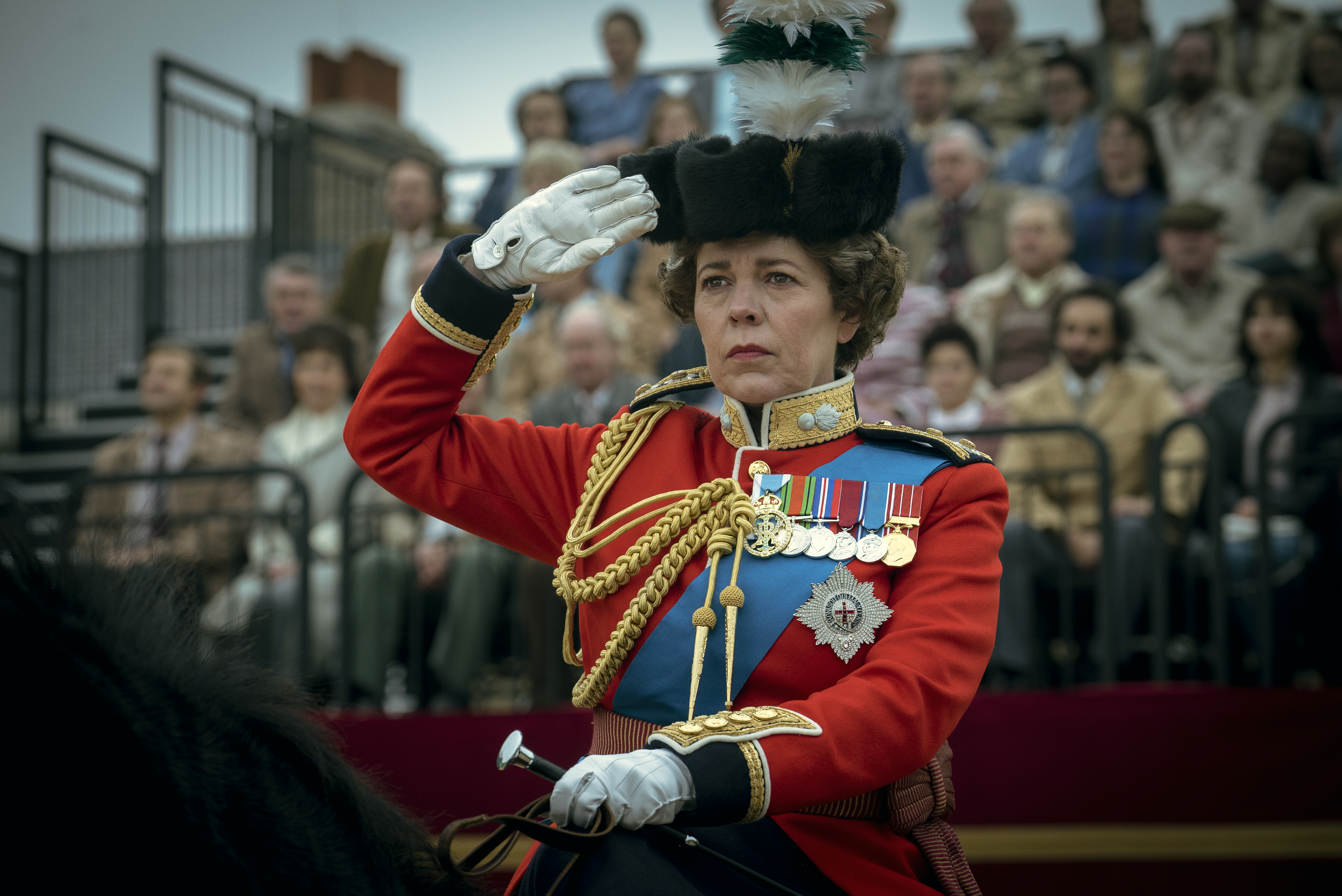 a woman in a military uniform is saluting in front of a crowd