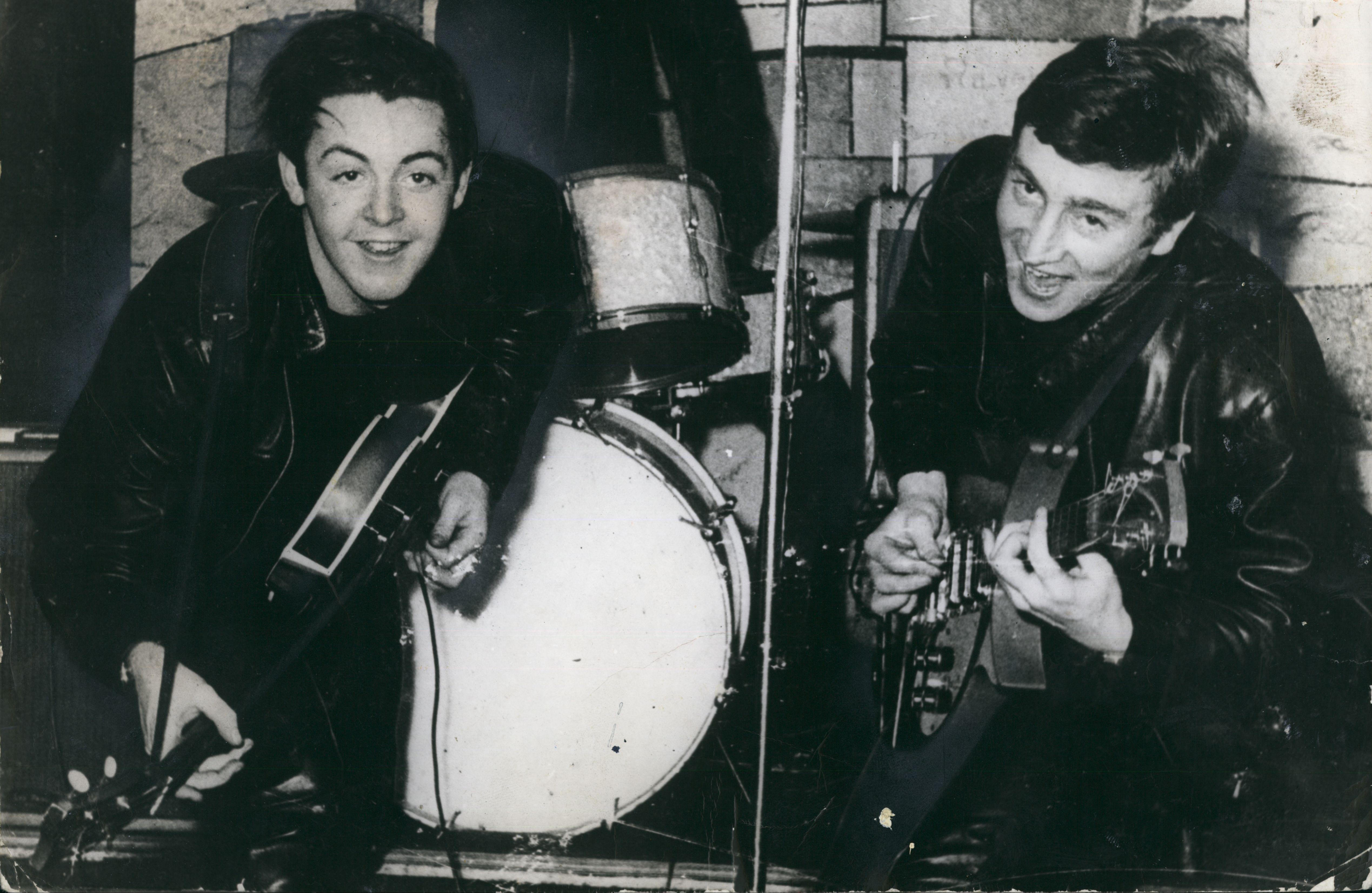 Black and white photo of Paul McCartney and John Lennon playing guitars.