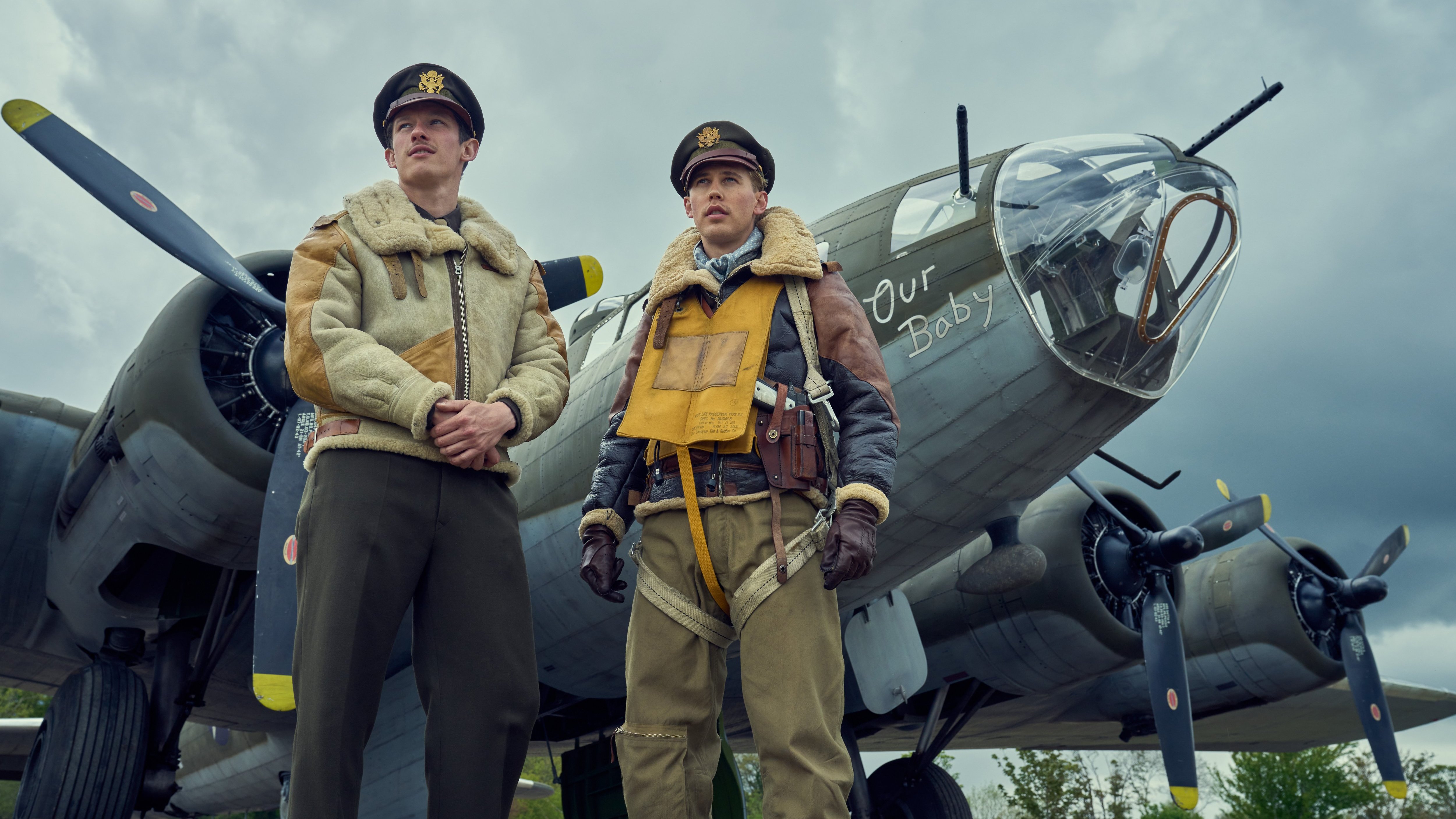 two men standing in front of a plane that says our baby