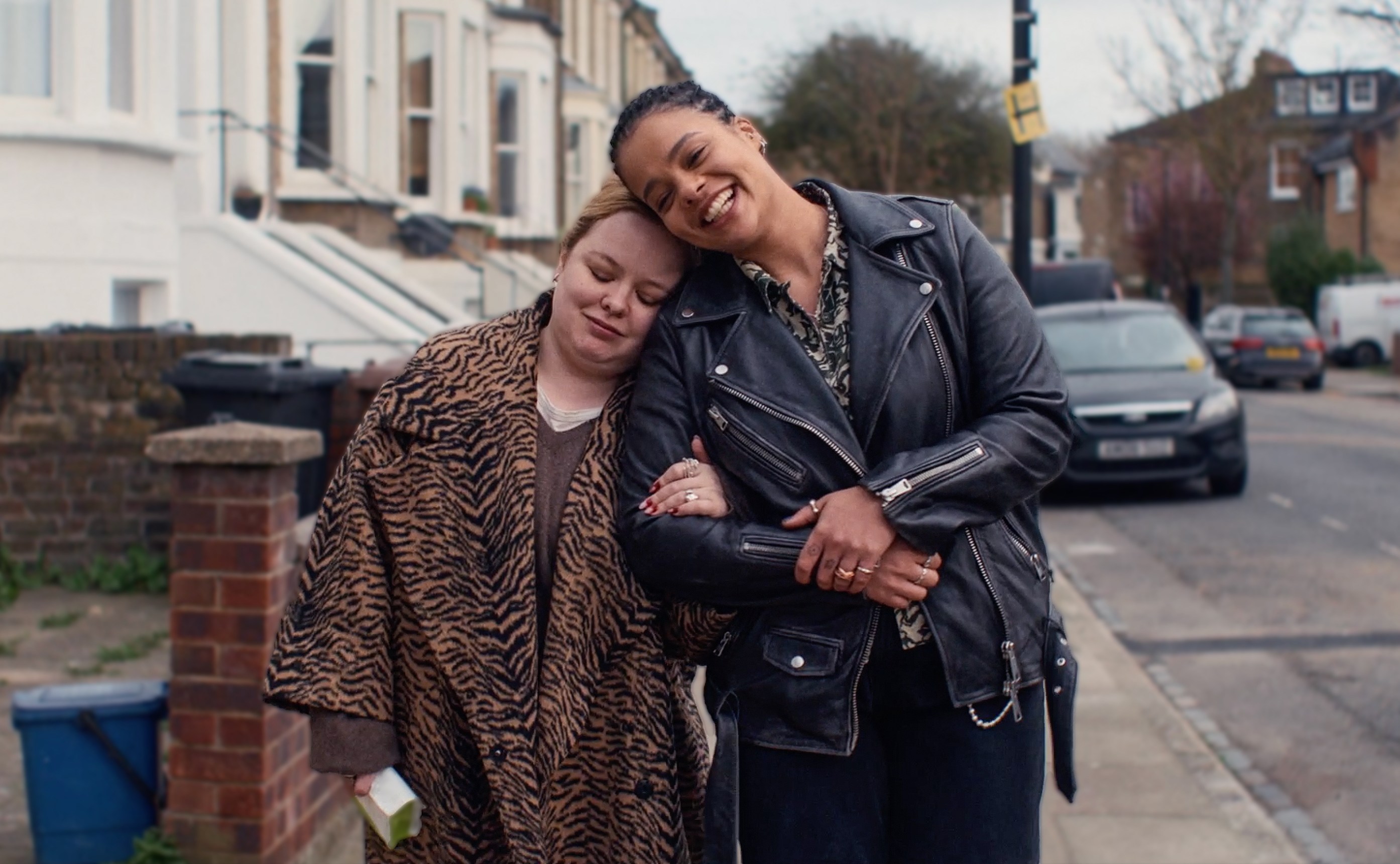A woman in a leather jacket is hugging another woman.