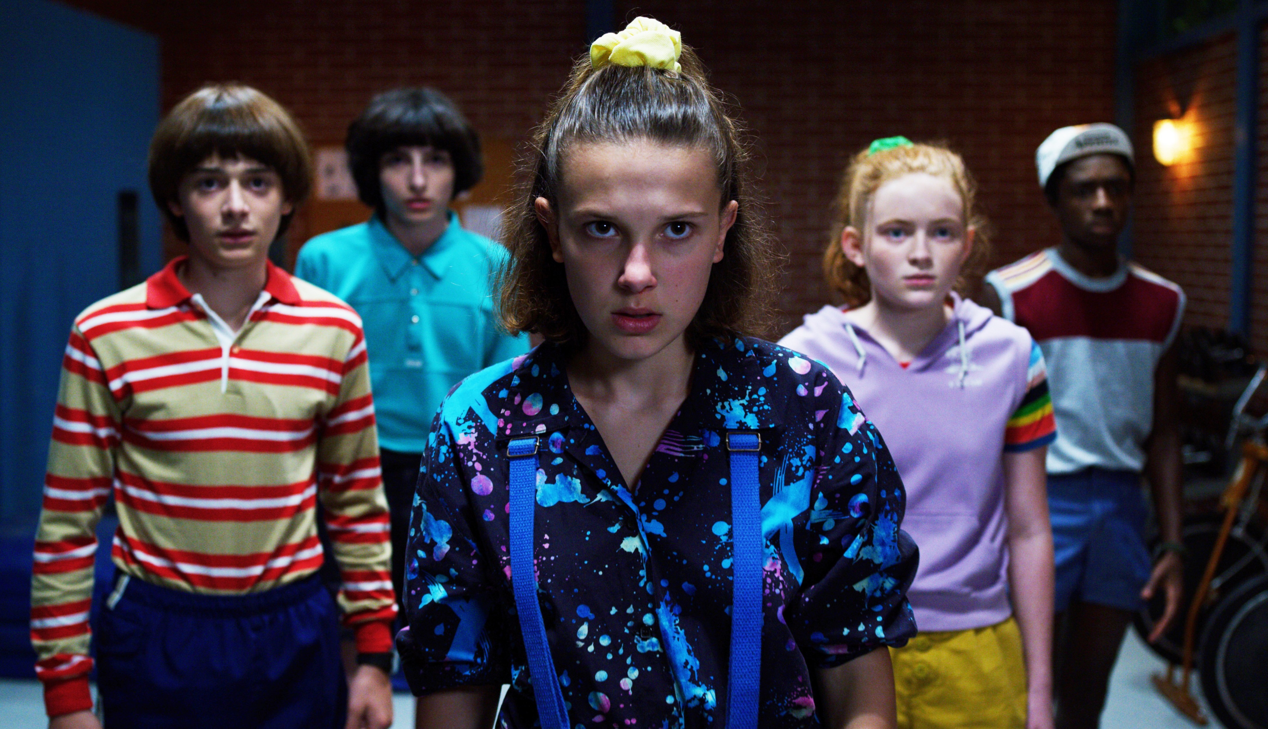 a group of people are standing in a room and one of them has a ponytail