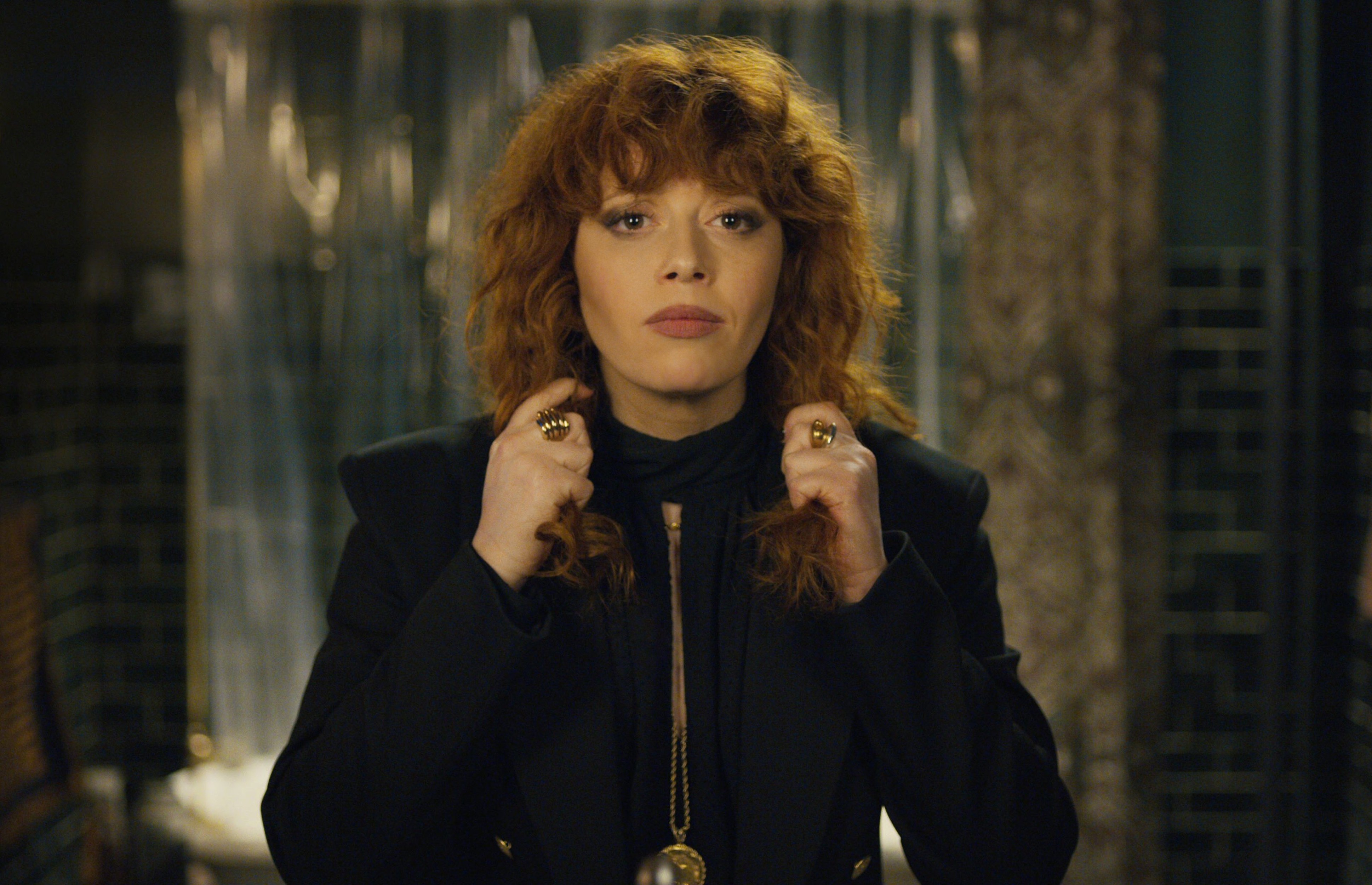 a woman with red hair is wearing a black jacket and gold rings