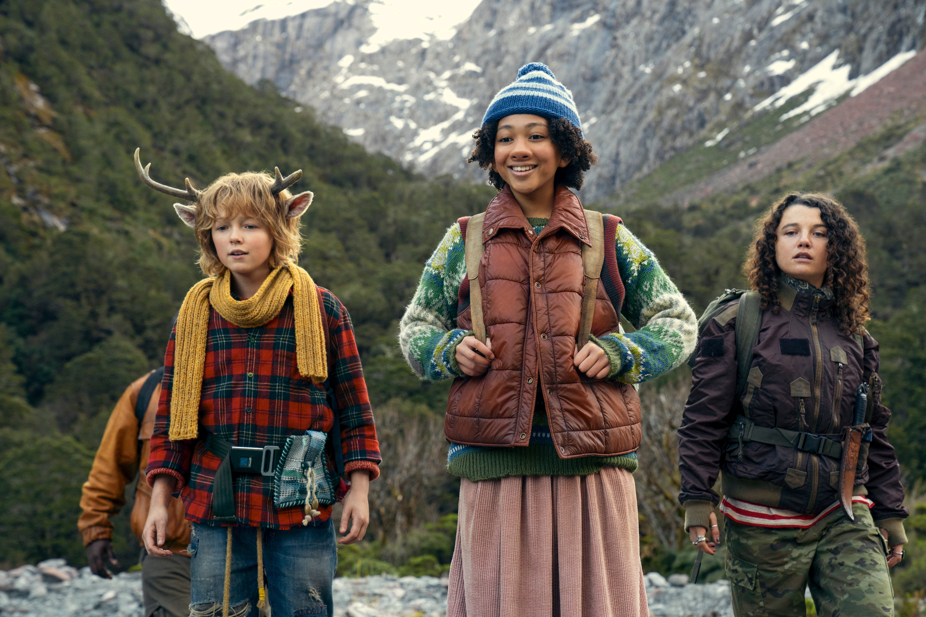 a boy with antlers is standing next to two girls